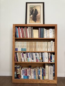 Bookshelf with Japanese-language Bakumatsu and Meiji Restoration history volumes and framed portrait of Katsu Kaishū